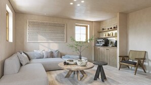 Una sala de estar moderna con un sofá, una mesa redonda de centro, una planta en maceta y una silla de madera.