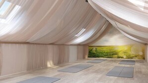 Un estudio de yoga con piso de madera, tapetes de yoga y un mural de un paisaje.