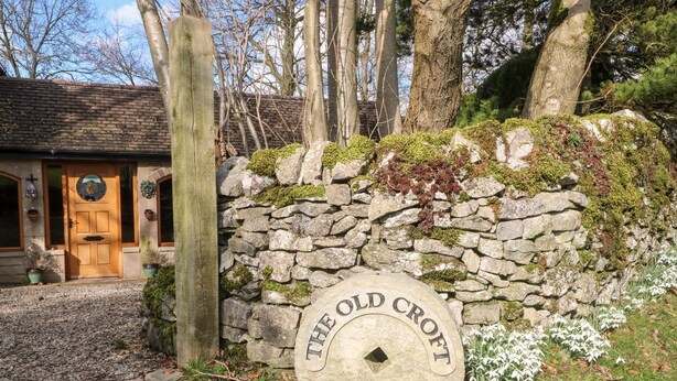 A stone wall with a sign reading "The Old Croft" and a wooden door. - The Old Croft (Buxton)