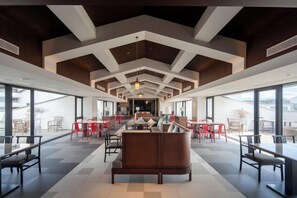 Un hall d’entrée spacieux avec un espace salon central, de grandes fenêtres et un design de plafond moderne.