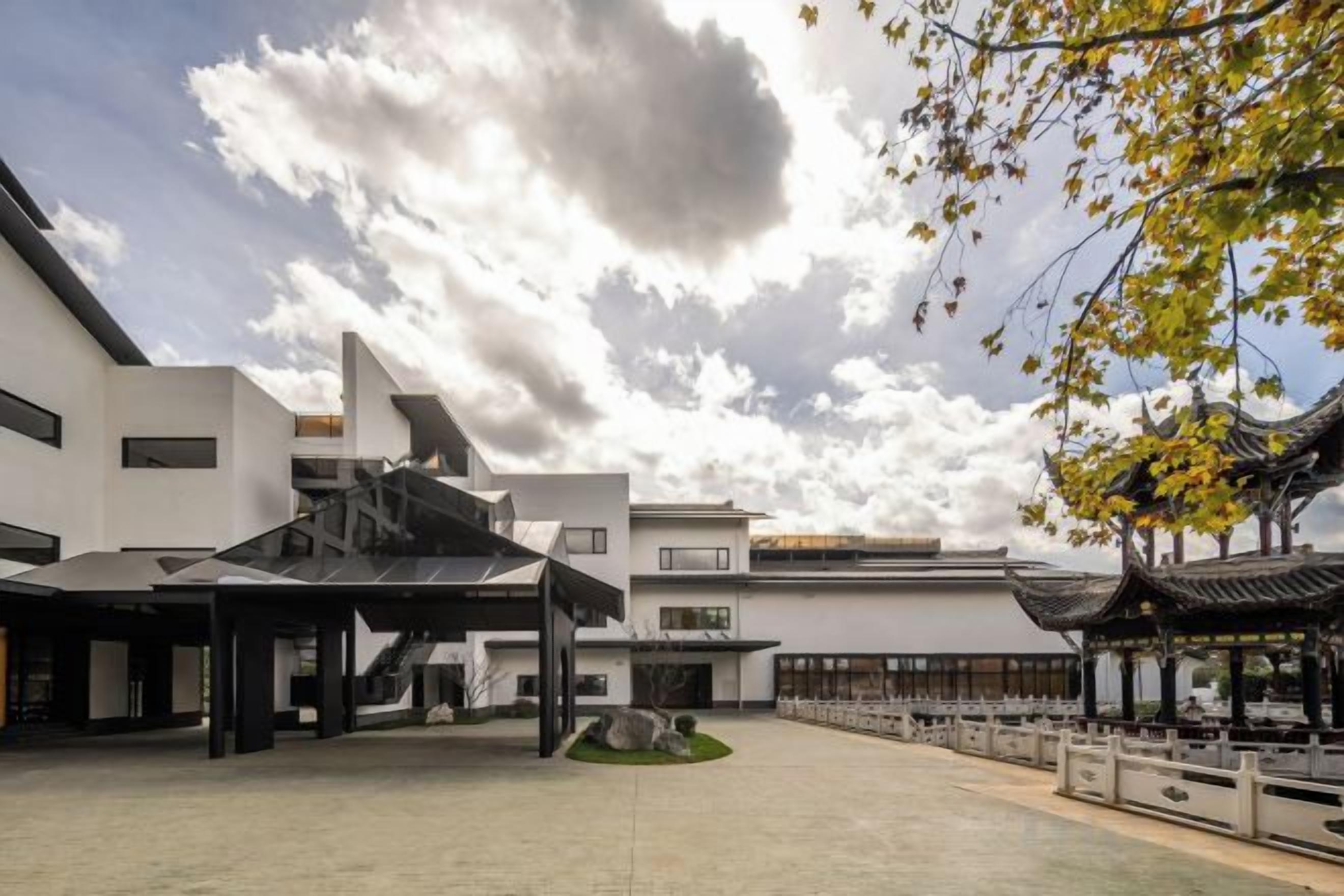 A courtyard with modern buildings, a traditional pavilion, and a clear sky.