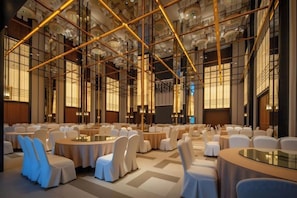 A spacious conference room with round tables and chairs, large windows, and a modern ceiling design.