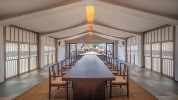 A long dining table with chairs, a high ceiling, and sliding doors on the sides.