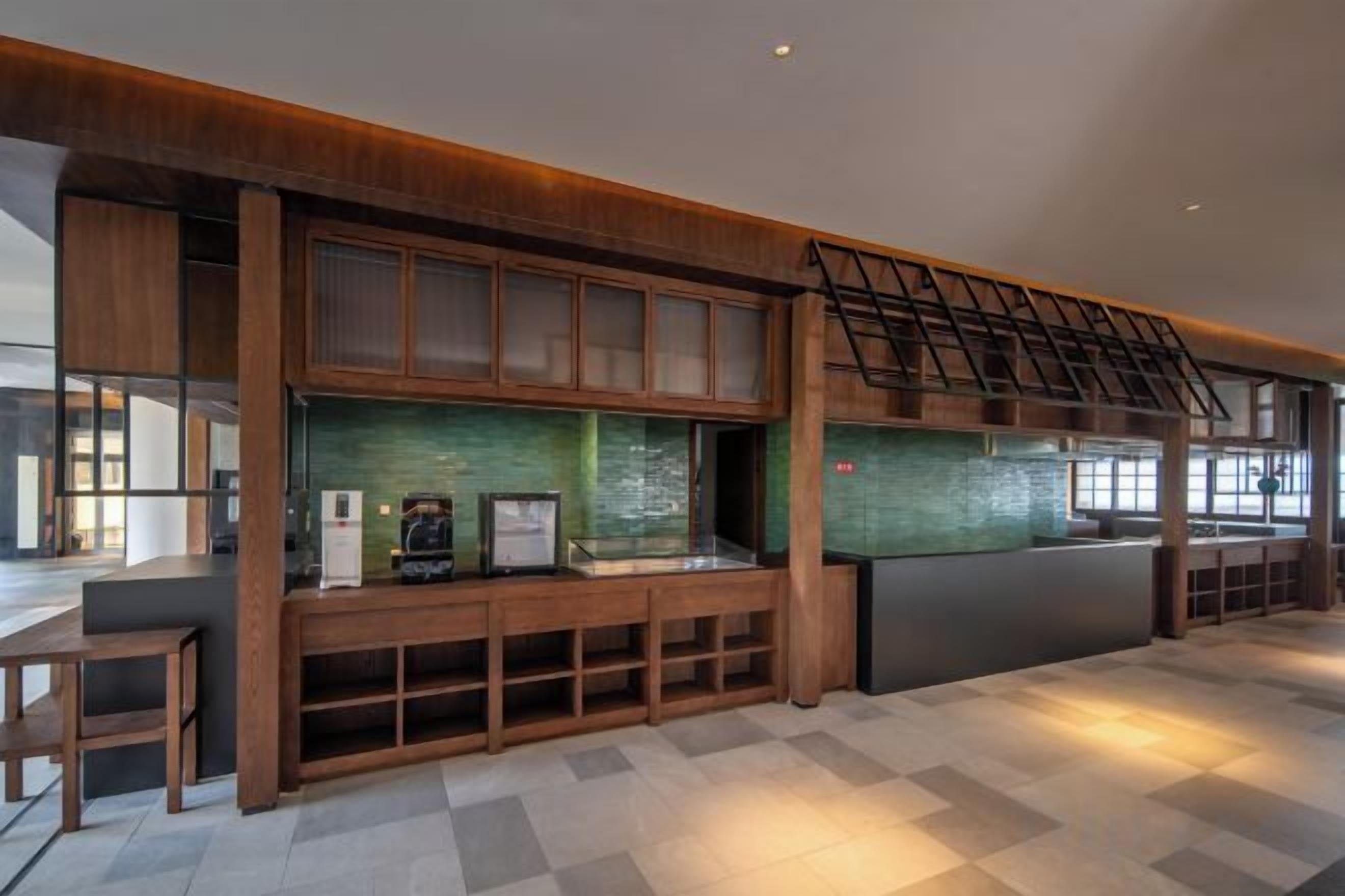 A modern interior with a wooden counter, a green backsplash, and a staircase.