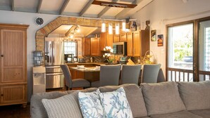 A cozy kitchen with wooden cabinets, a built-in oven, and a dining area with a gray sofa and patterned cushions. - ST.JOHN, VIRGIN ISLANDS!  2 BEDROOM, 1.5 BATH, BEAUTIFUL TROPICAL GARDENS! (St. John)