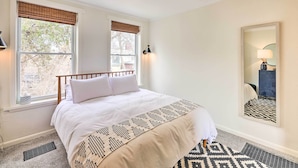 A neatly made bed with white linens, a patterned throw, and a window with a view of trees and a building outside. - Cincinnati Vacation Rental: 6 Mi to Downtown! (Cincinnati)