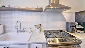 A modern kitchen with a stainless steel stove, white tiled backsplash, and a coffee machine. - Cincinnati Vacation Rental: 6 Mi to Downtown! (Cincinnati)