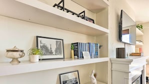 A bookshelf with framed pictures, books, and decorative items. - Cincinnati Vacation Rental: 6 Mi to Downtown! (Cincinnati)