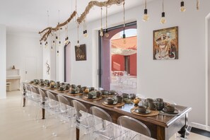 Enjoy meals in this stylish dining area with a long table, clear chairs, and unique light fixture.