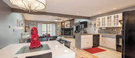 A modern kitchen with white cabinets, a black refrigerator, and a dining area with a white table and chairs.
