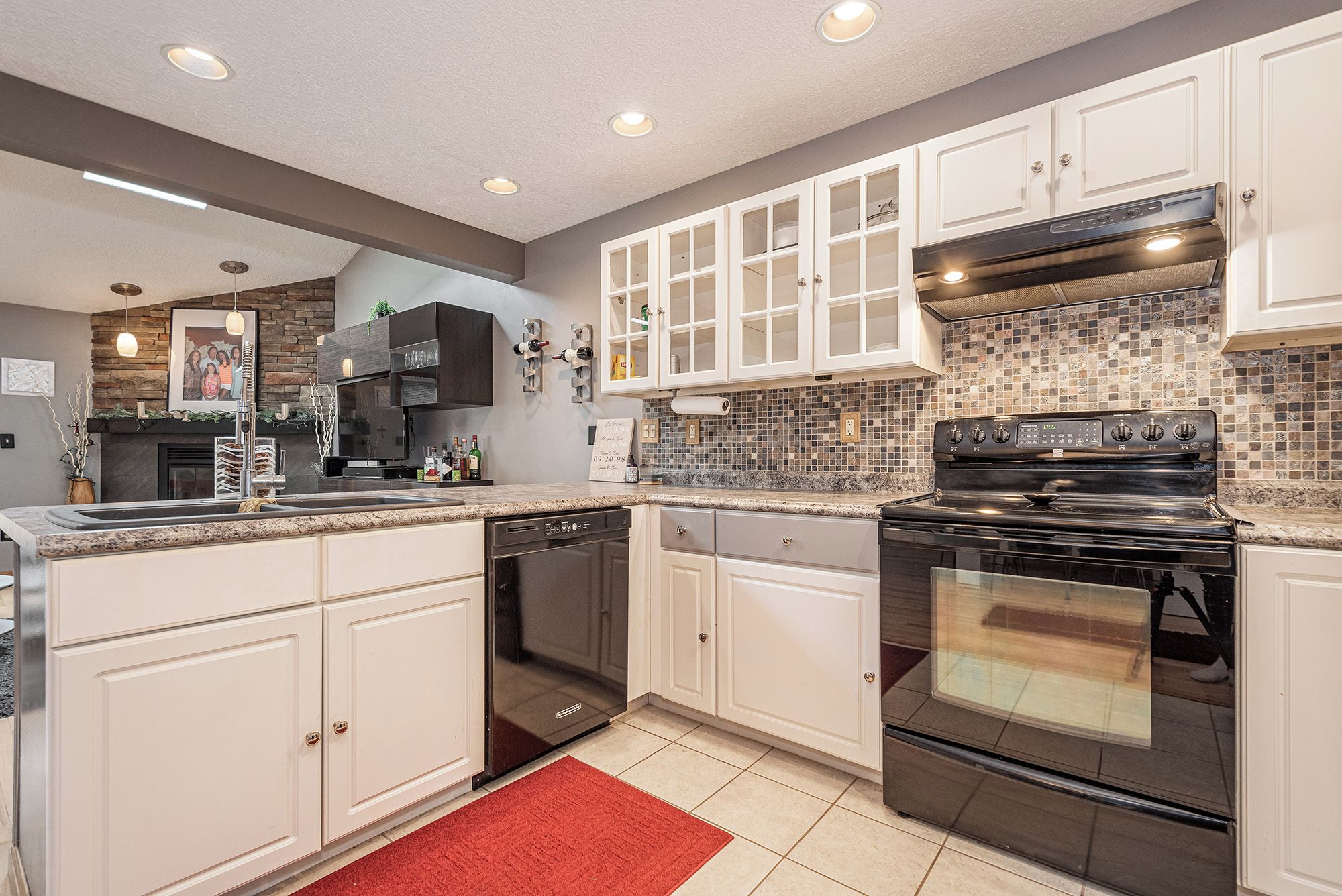 Una cocina moderna con armarios blancos, una estufa negra y un salpicadero de azulejos.