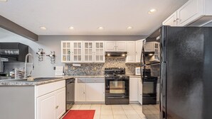 A kitchen with white cabinets, a black refrigerator, a stove, and a microwave. - Laurel Brook 39 by Taylor Made Deep Creek (Oakland)