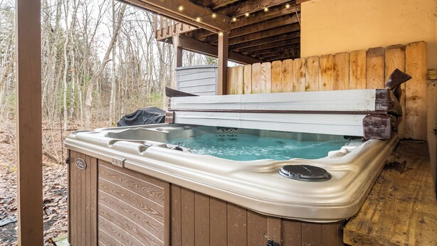 A hot tub with a wooden deck and a wooden fence in a wooded area. - Laurel Brook 39 by Taylor Made Deep Creek (Oakland)
