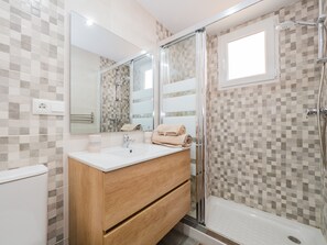 Ein modernes Badezimmer mit Dusche, Waschbecken und Spiegel.