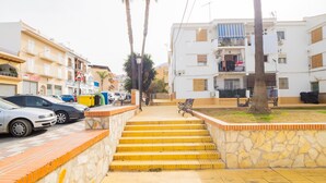 A street with steps leading to a building with balconies, parked cars, and palm trees. - Cubo's Ideal Alhaurin Job / urban / ideal for teleworking (Alhaurín el Grande)