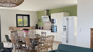 A modern kitchen with white cabinets, a stainless steel range hood, and a built-in oven.