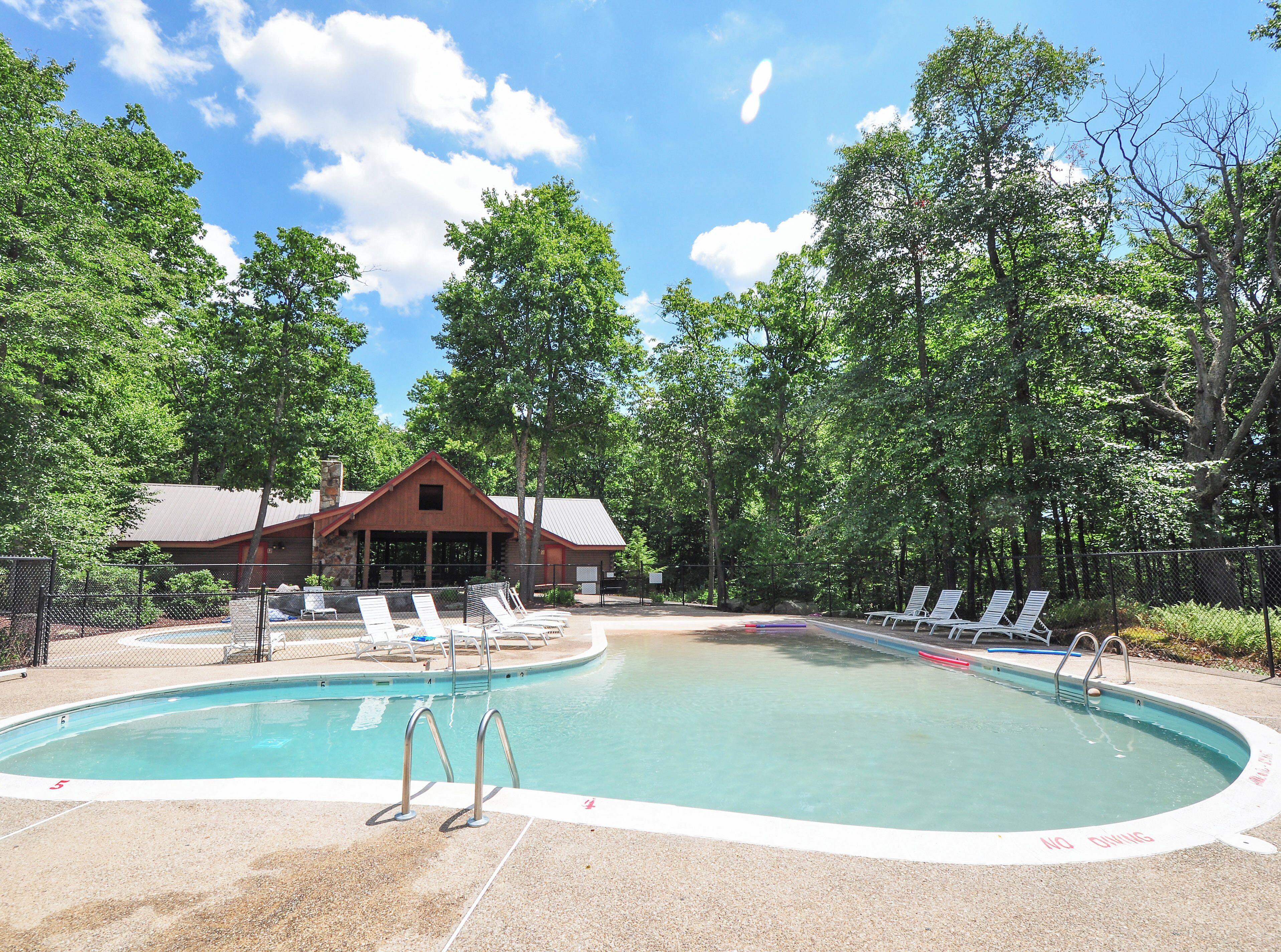 A pool area with lounge chairs and a building in the background.