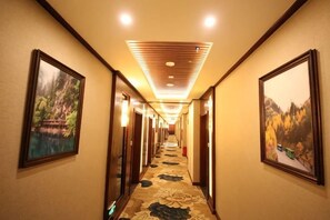 A hotel hallway with framed pictures on the walls, a patterned carpet, and a ceiling with recessed lighting. - Dege Shandi Hotel (Dege)