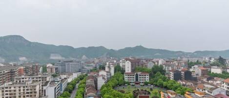 A cityscape with multiple buildings, a central road, and a mountainous backdrop.