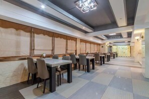 A restaurant with multiple tables and chairs, a patterned floor, and a modern ceiling design. - Chang Jin Hotel, Luxi (Luxi)