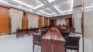 Ein Konferenzraum mit einem langen Tisch und Stühlen, deckenmontierten Leuchten und einem großen Spiegel an einer Wand.