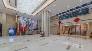 Eine großzügige Lobby mit hoher Decke, einem Empfangstresen, einer Verkaufsmaschine und einer Treppe, die in einen oberen Bereich führt.