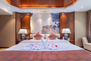 Una habitación de hotel con una cama grande, dos mesitas de noche con lámparas y un adorno de pared decorativo.