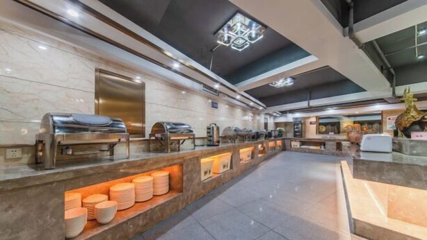 Eine moderne Hotelhalle mit einer langen Rezeption, mehreren Kaffeemaschinen und einer dekorativen Giraffenskulptur.