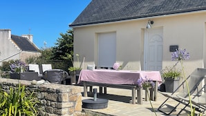 A patio area with a table set for dining, outdoor seating, and potted plants.