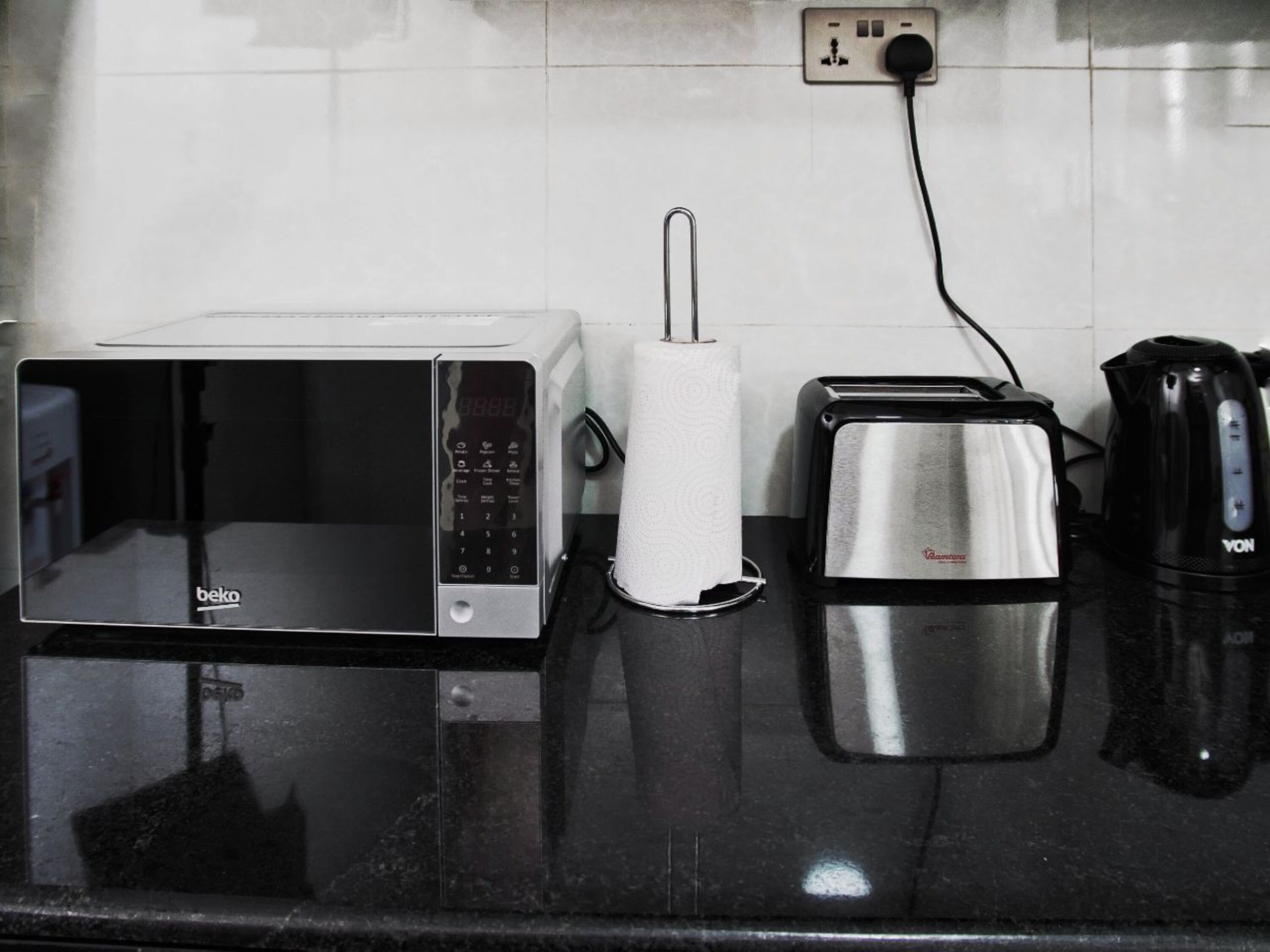A kitchen with a microwave, toaster, and kettle on a black countertop.