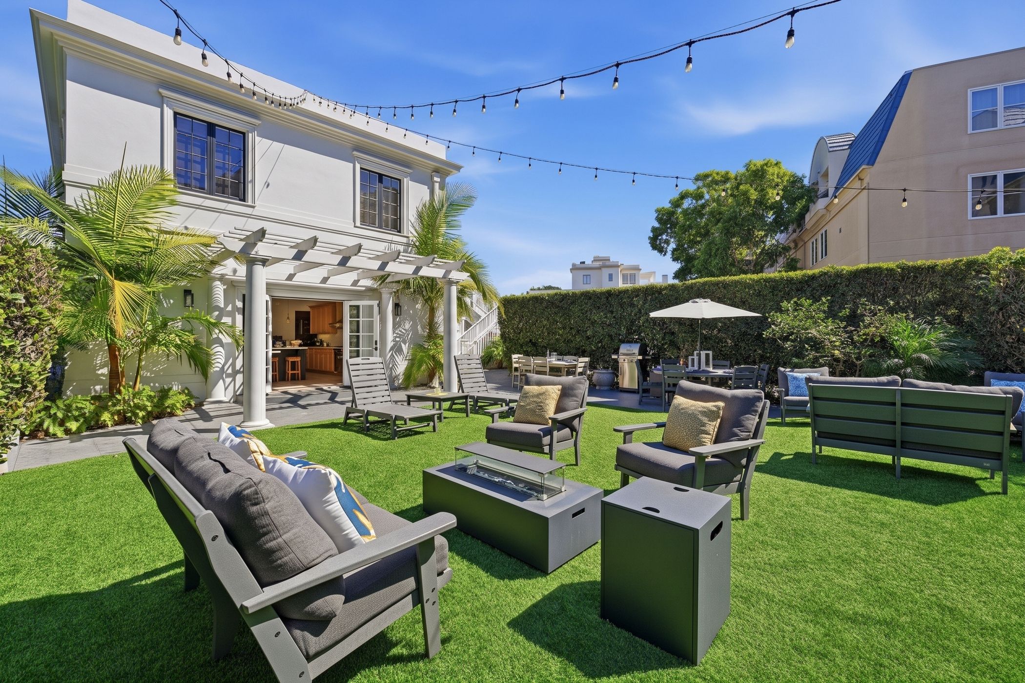 A patio area with outdoor furniture, a pergola, and string lights.