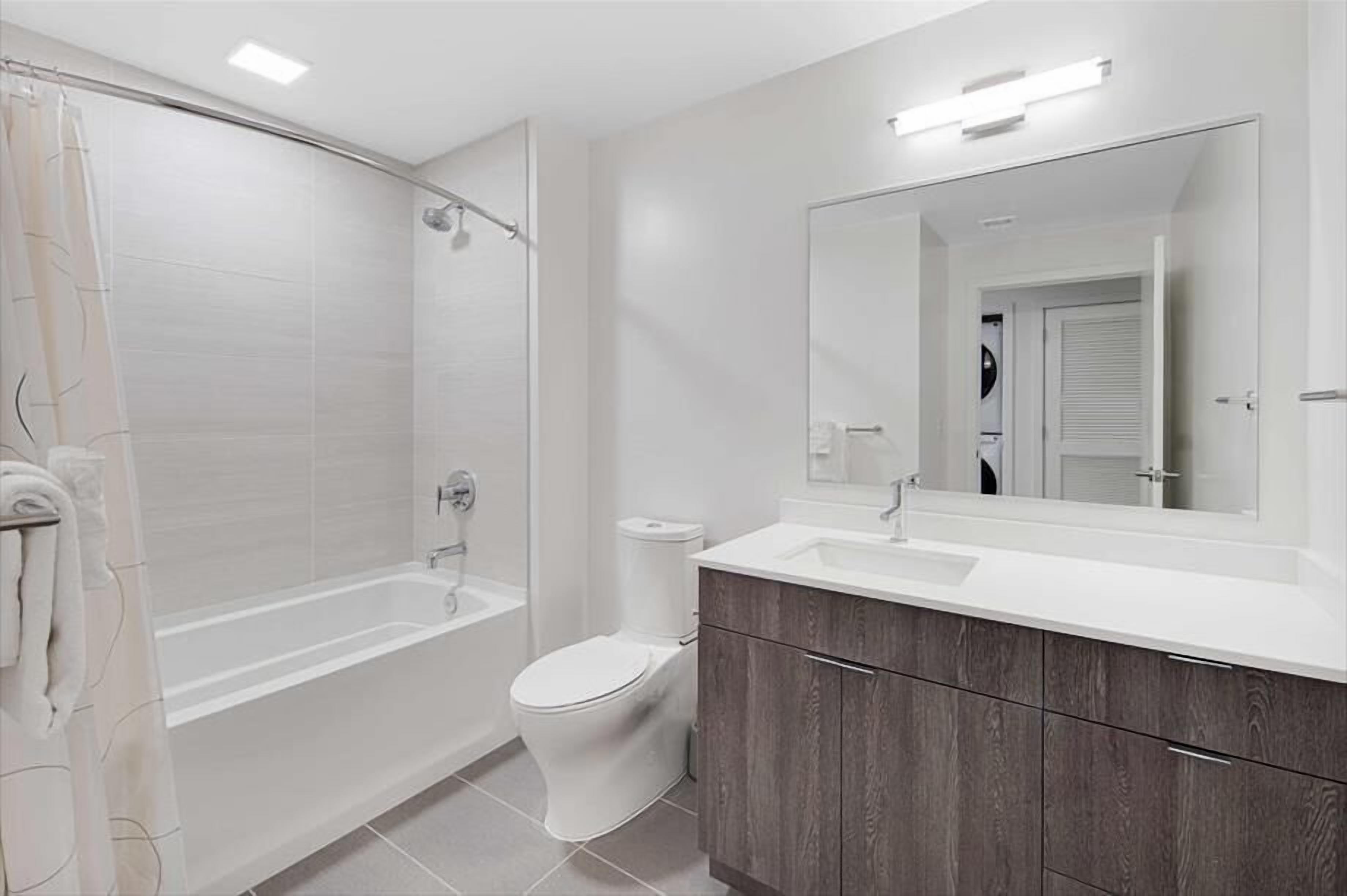 Une salle de bain moderne équipée d’une baignoire, de toilettes et d’un meuble-lavabo.