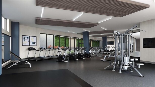 Une salle de sport moderne équipée de nombreux tapis de course, d’appareils de musculation elliptiques et de machines de musculation.