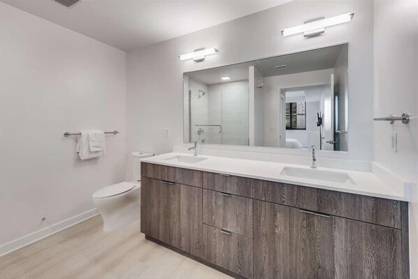 Un baño moderno con lavamanos doble, inodoro y un espejo grande.