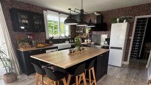 A modern kitchen with a central island, black bar stools, and a brick wall. - A 3-star family-run inn with a pool: "La Parenthèse," just outside La Rochelle (Villedoux)