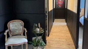 A hallway with a chair, a small table with a plant, and a framed picture on the wall. - A 3-star family-run inn with a pool: "La Parenthèse," just outside La Rochelle (Villedoux)