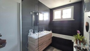 A modern bathroom with a glass shower enclosure, a double sink vanity, a bathtub, and a window providing natural light. - A 3-star family-run inn with a pool: "La Parenthèse," just outside La Rochelle (Villedoux)