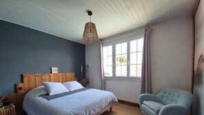 A bedroom with a bed, a chair, a hanging light fixture, and a window. - A 3-star family-run inn with a pool: "La Parenthèse," just outside La Rochelle (Villedoux)