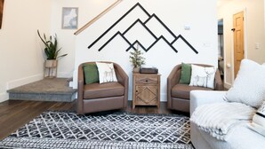 En stue med to sofaer, et sofabord, et vægur og en geometrisk billedvæg.