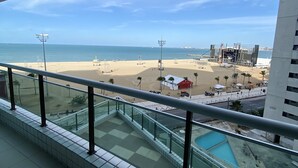 A view from a balcony overlooking a beach with a pool, a sandy area, and a building under construction.