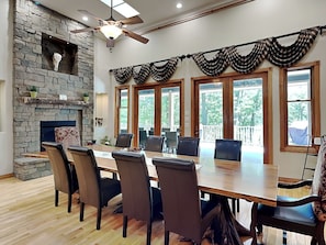 A conference room with a long table, chairs, a stone fireplace, and large windows.