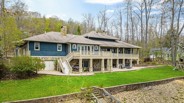 A two-story house with a covered porch, a stone chimney, and a small front yard.