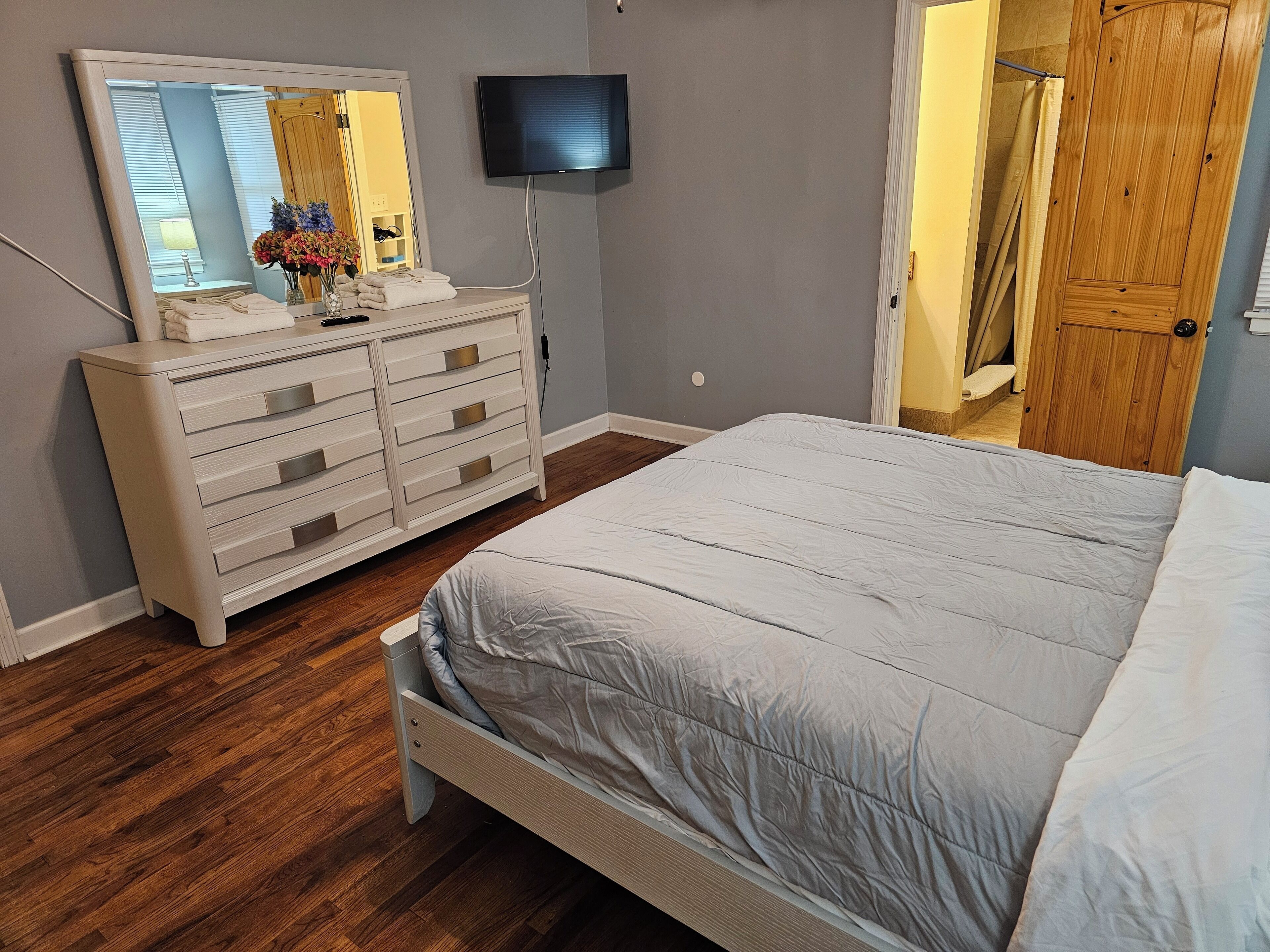 Ein Schlafzimmer mit einem Bett, einem Schminktisch, einem Spiegel und einem Fernseher.