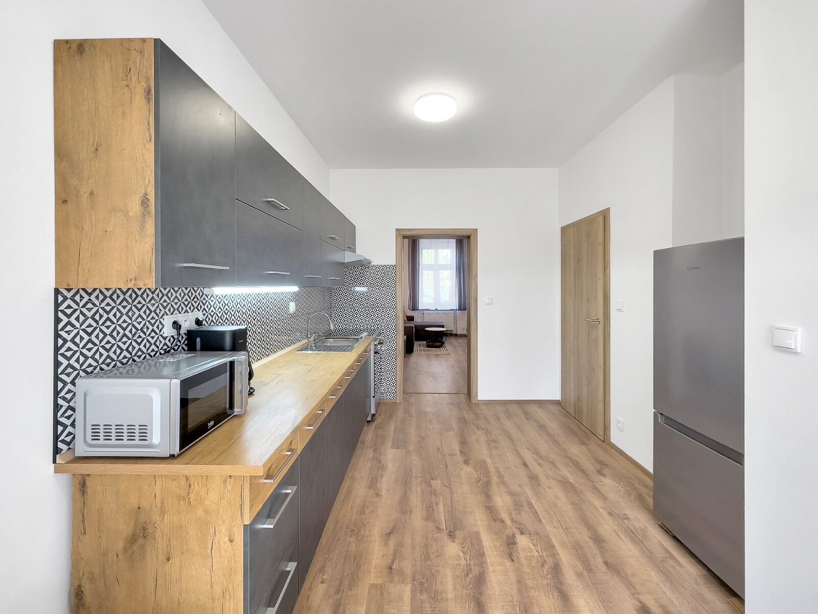 A modern kitchen with a wooden countertop, grey cabinets, and a patterned backsplash.