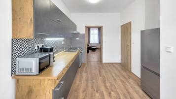 A modern kitchen with a wooden countertop, grey cabinets, and a patterned backsplash.