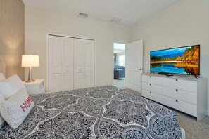 A bedroom with a bed, a TV, a dresser, and a door. - Family & Dog-Friendly ChampionsGate Villa | Private Pool, Game Room & Themed Rooms (Champions Gate)