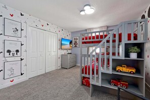 Ein Kinderzimmer mit Etagenbett, Kommode, Fernseher und Wanddekorationen.