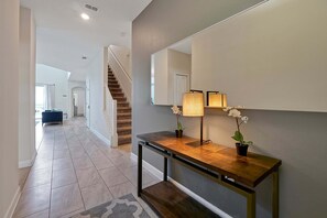 A hallway with a wooden console table, a mirror, and two potted orchids.