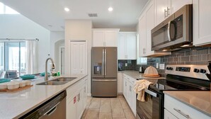 Una cocina moderna con electrodomésticos de acero inoxidable, armarios blancos y lavavajillas.