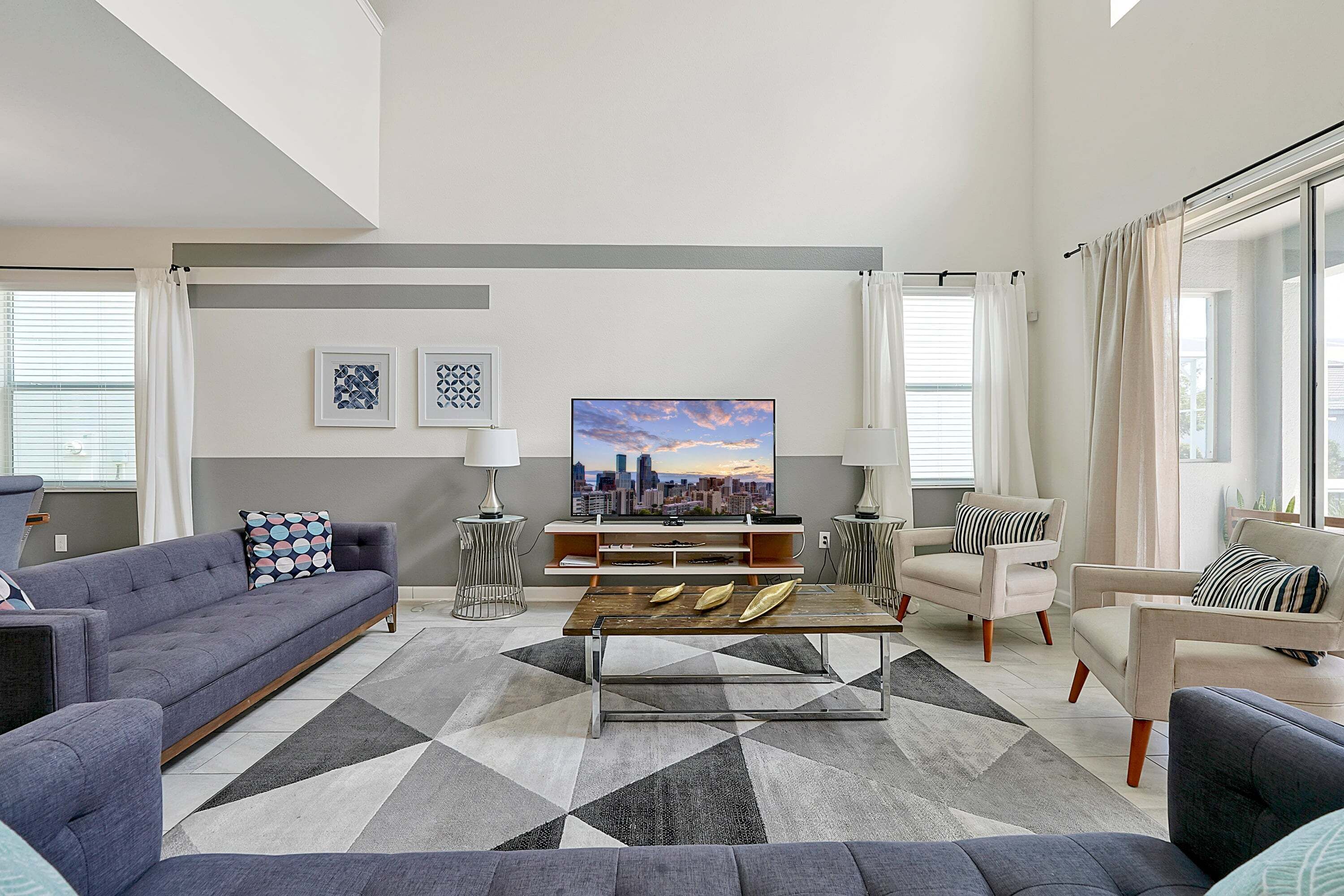 A modern living room with a sofa, armchairs, a coffee table, and a TV.